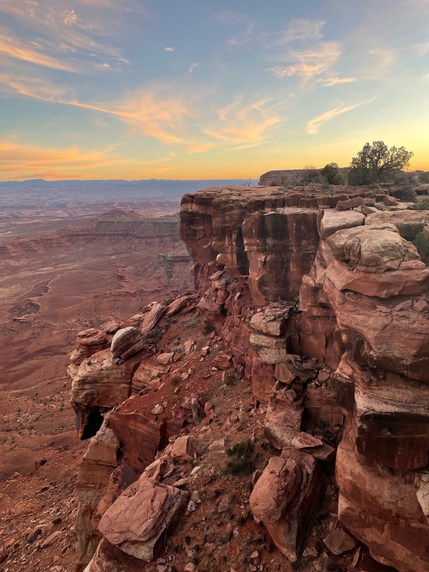 Cliff-edge overlook above red sandstone canyons near Moab at sunset with pastel clouds