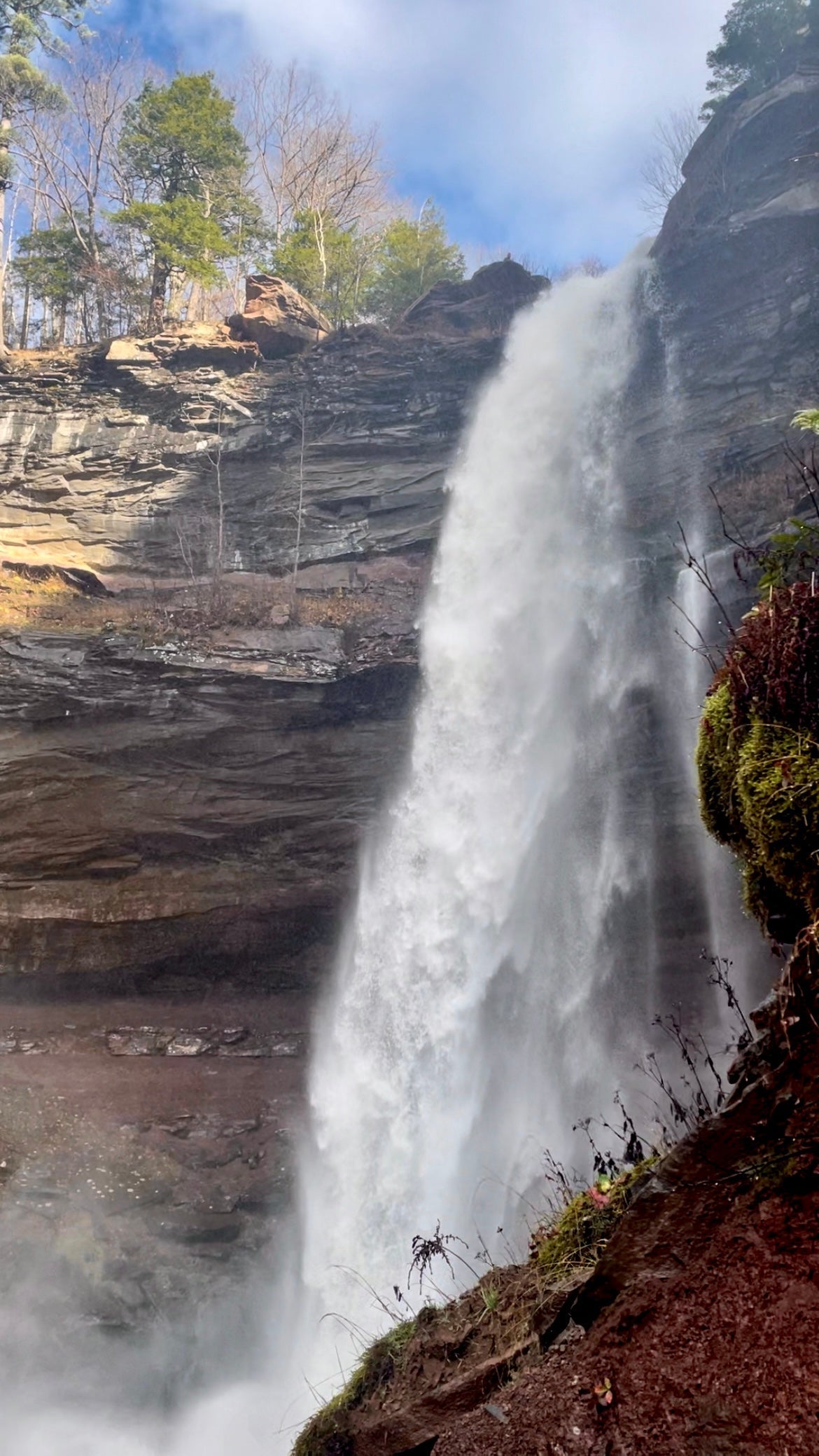 Waterfall plunges over a rocky cliff in the Catskills, surrounded by forest and mist