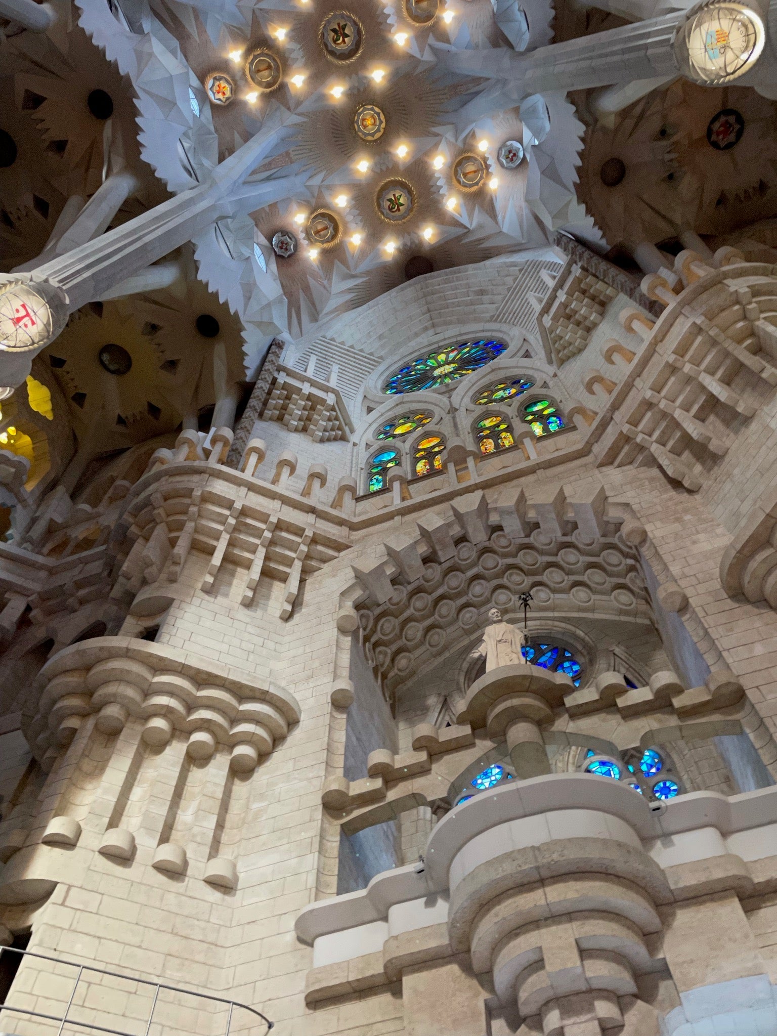 Interior of Barcelona’s Sagrada Familia with ornate stone columns, geometric ceilings, and colorful stained glass windows