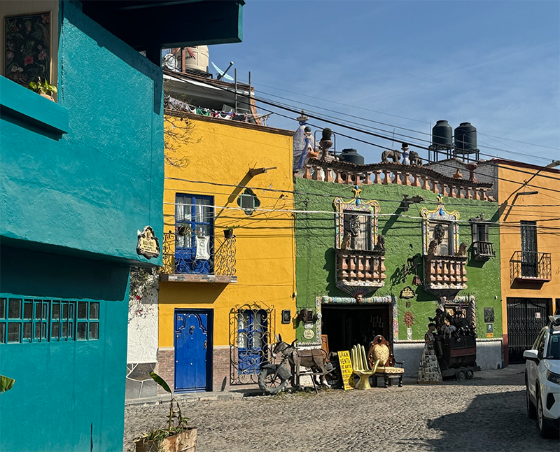 Colorful buildings with balconies line a cobblestone street in San Miguel de Allende