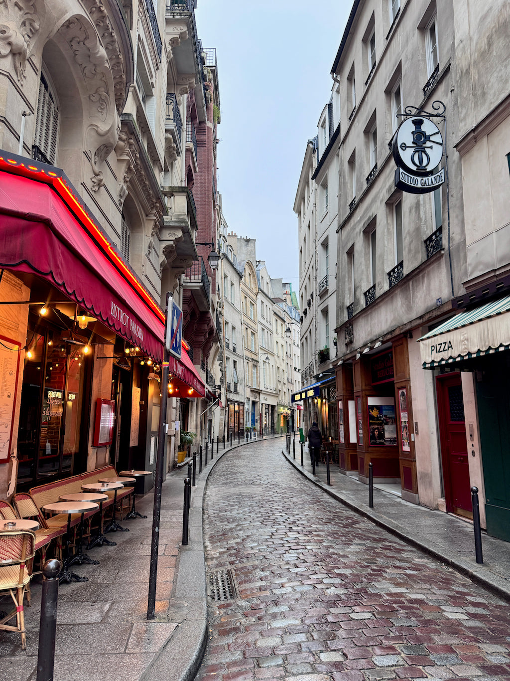 Paris cobblestone street lined with cafes, restaurants, and historic buildings