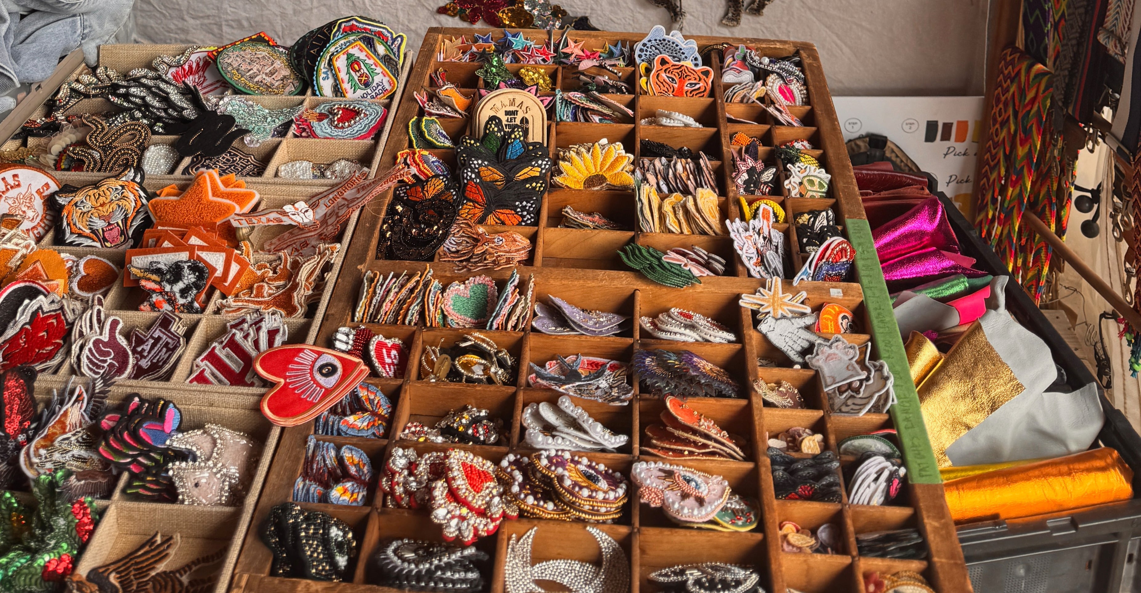 Colorful embroidered patches and accessories arranged in trays at a Round Top, Texas market