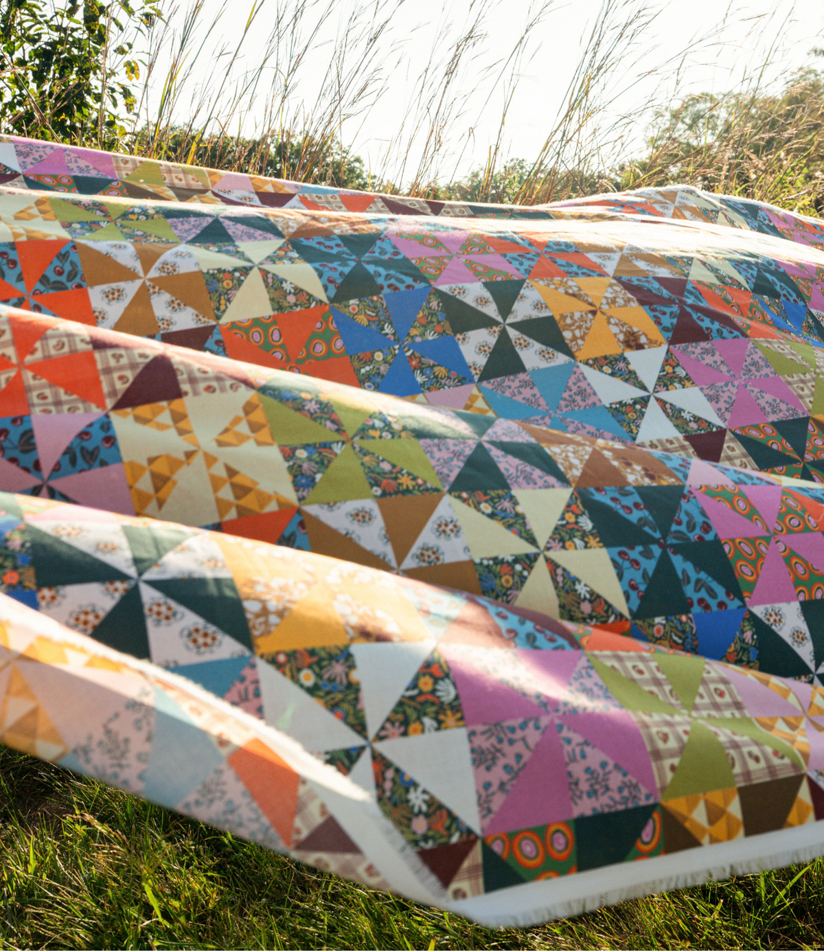 Draped view of Calico Cotton Fabric by the Yard showcasing colorful patchwork pattern among sunlit grasses