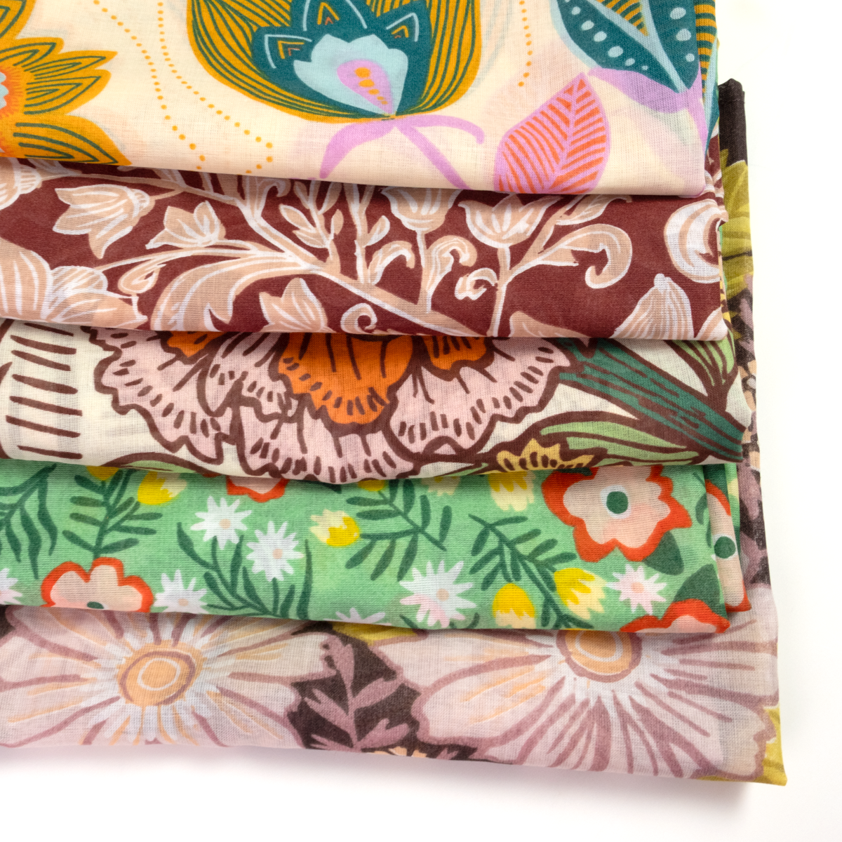 A stack of folded cotton bandanas with various floral and botanical patterns in earthy tones including green, brown, pink, orange, and cream.