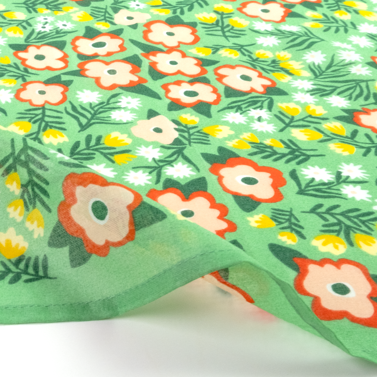 A close-up of a light green bandana with a dense floral pattern featuring orange, white, and yellow flowers with green leaves.