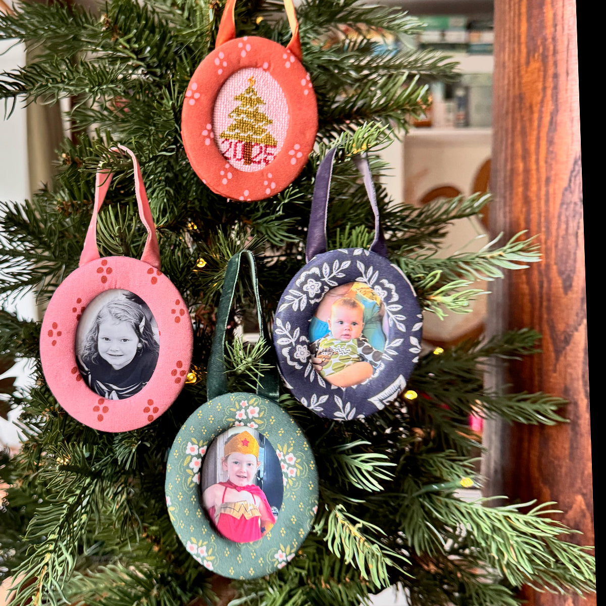 Several vintage round photo ornaments (pink, navy, green) hanging on a Christmas tree, each showing a small portrait or holiday illustration.