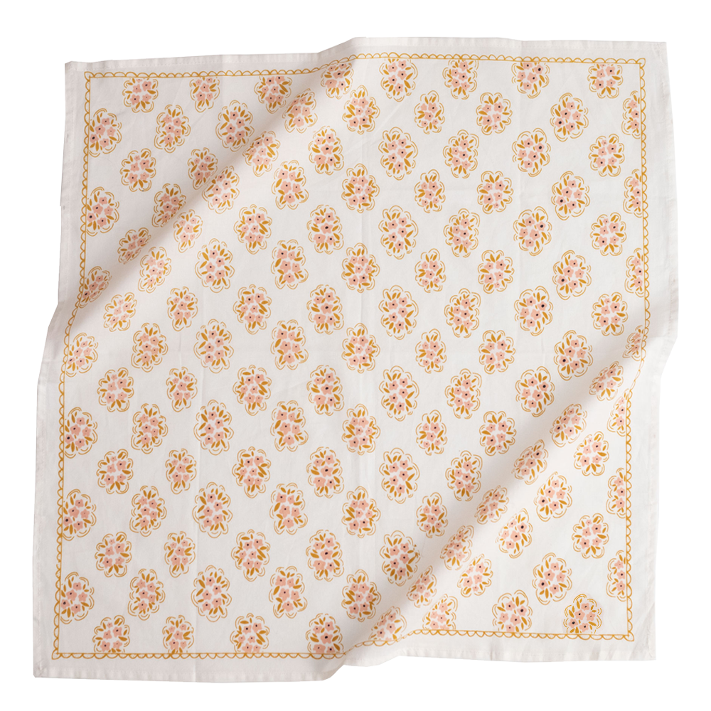 White square napkin printed with repeating pink and gold floral medallion motifs and scalloped gold border, slightly folded.