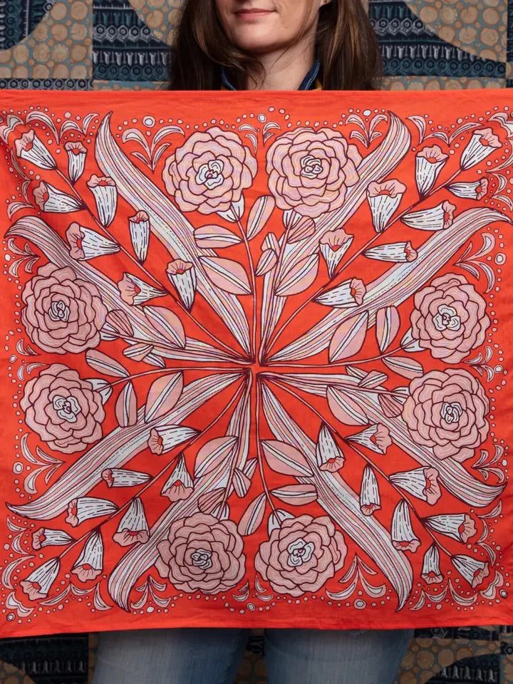 Front view of Greta cotton bandana in hot-red with white and pink-peach floral print held by a person