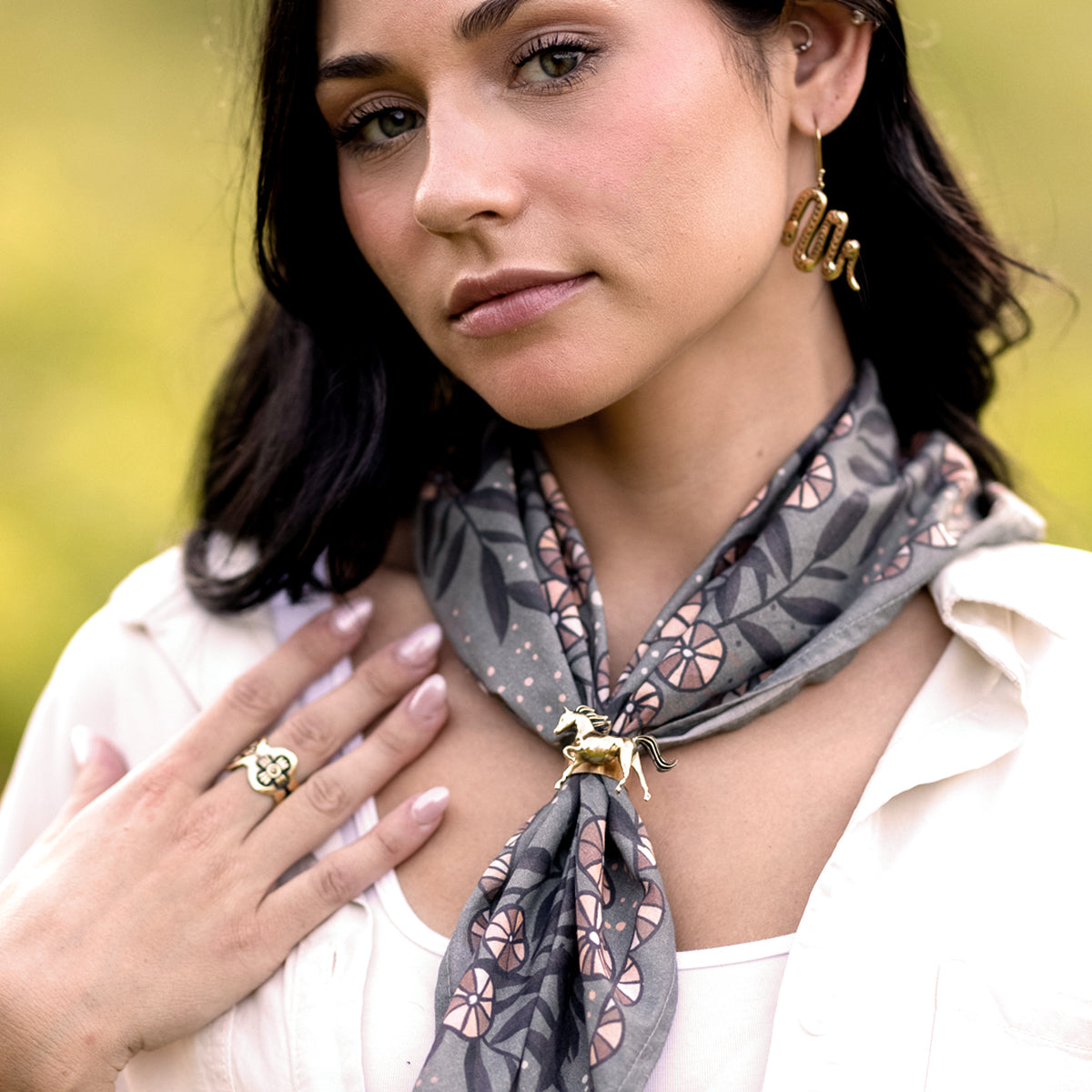 Woman wearing a patterned scarf with a horse brooch and jewelry