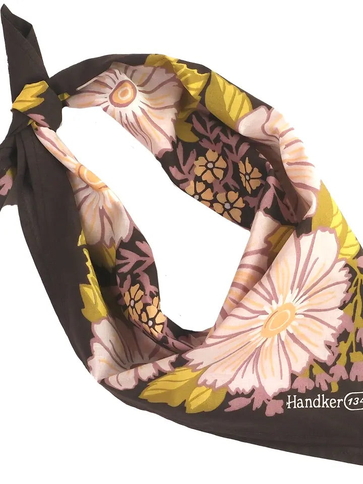 Angled view of Violet bandana tied in a loop showing peach-pink floral print with olive leaves on a dark violet background