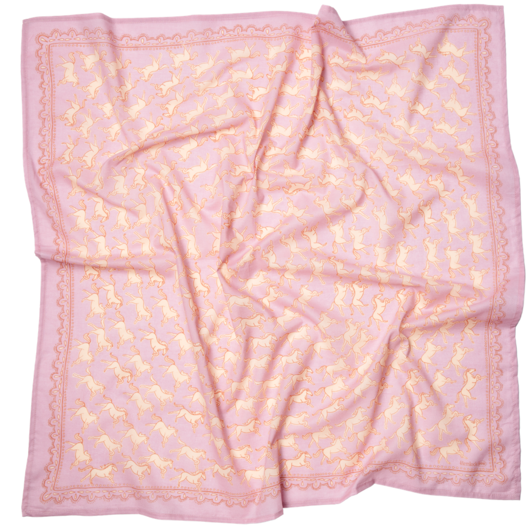 Pink silk square scarf with repeating cream unicorn motif, scalloped decorative border and soft folds.