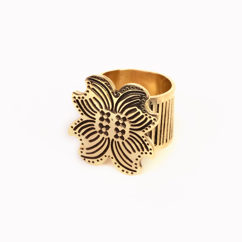 Gold wide-band ring with engraved five-petal floral motif and cutout details on white background