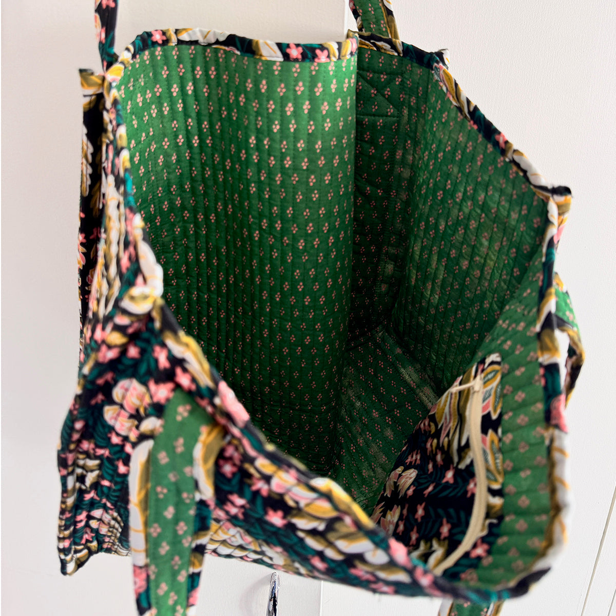 Open floral fabric tote bag showing green diamond-patterned interior, navy-pink floral exterior, and an inner pocket