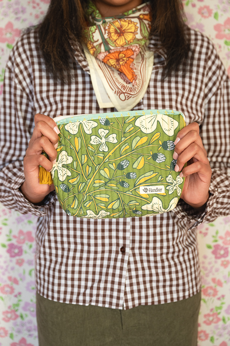 Woman holding a green floral-patterned pouch against a floral background