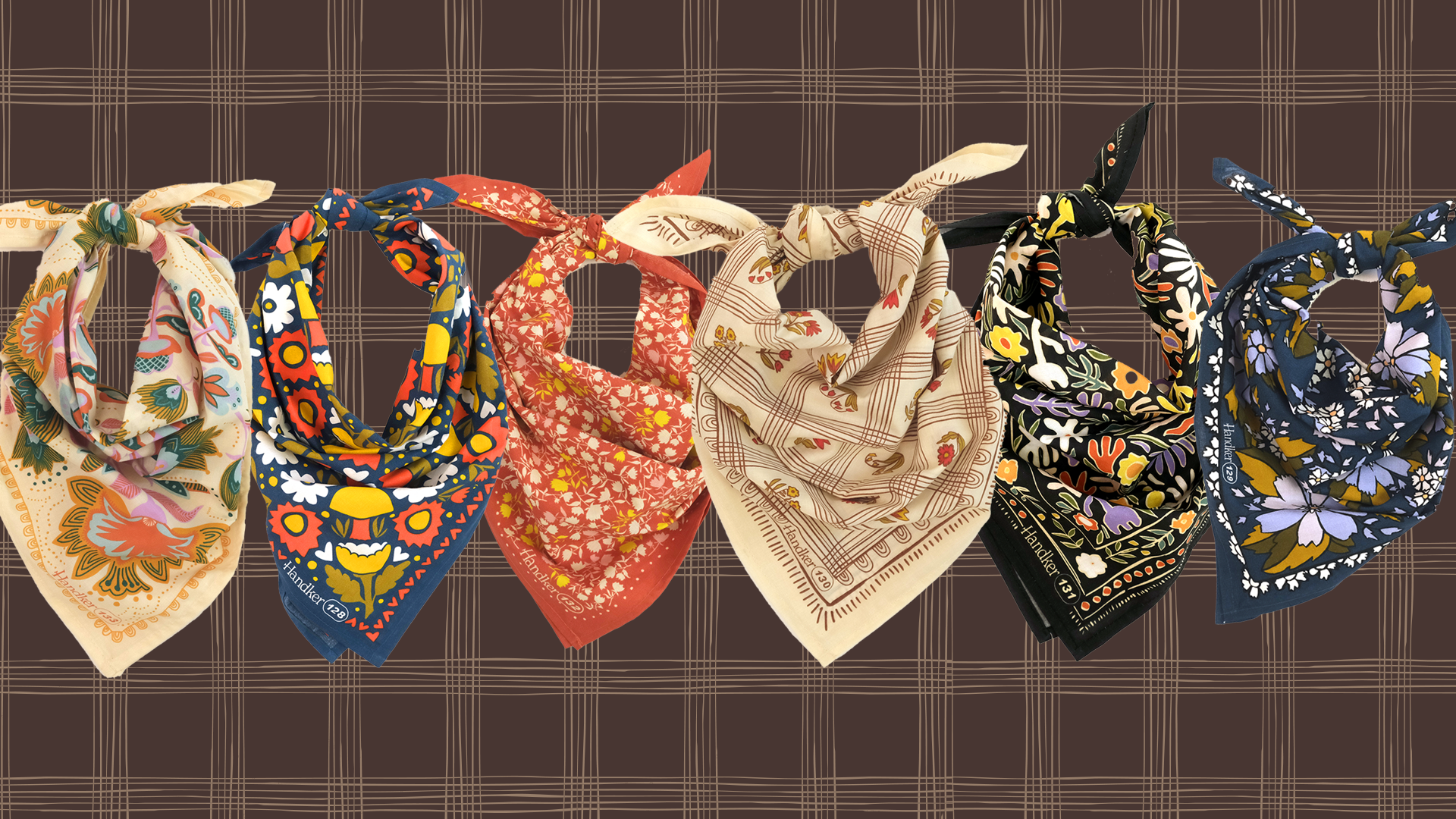 Front view of six Prairie Proper bandanas knotted showing floral and geometric prints on brown plaid background