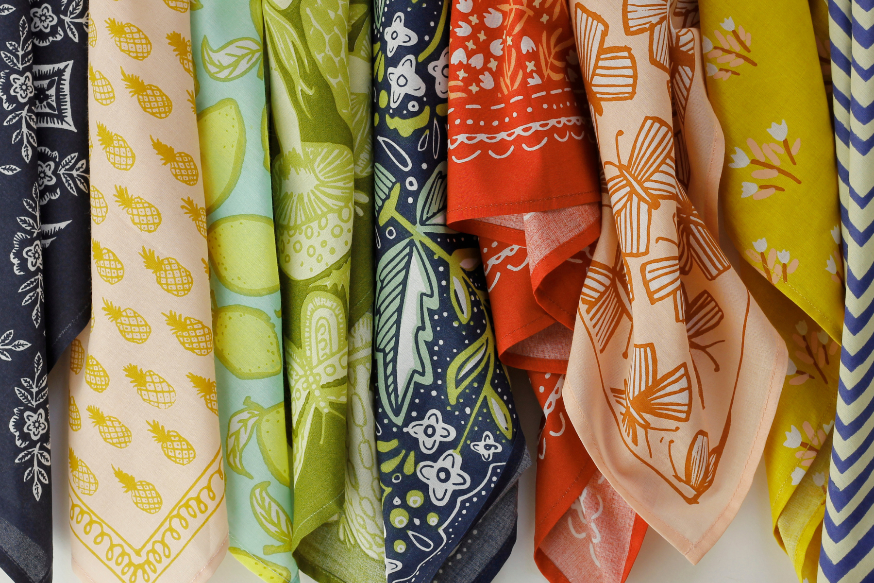 An array of multi-colored bandanas lying on a white backdrop