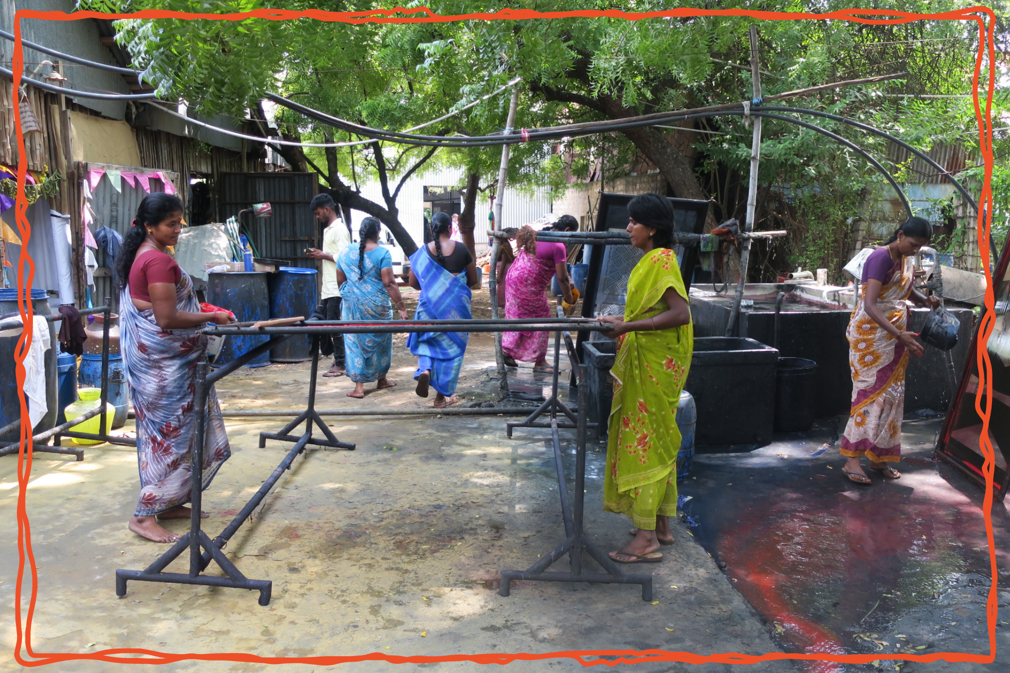 Women in colorful saris washing, dyeing, and stretching fabric at an outdoor textile workshop in India