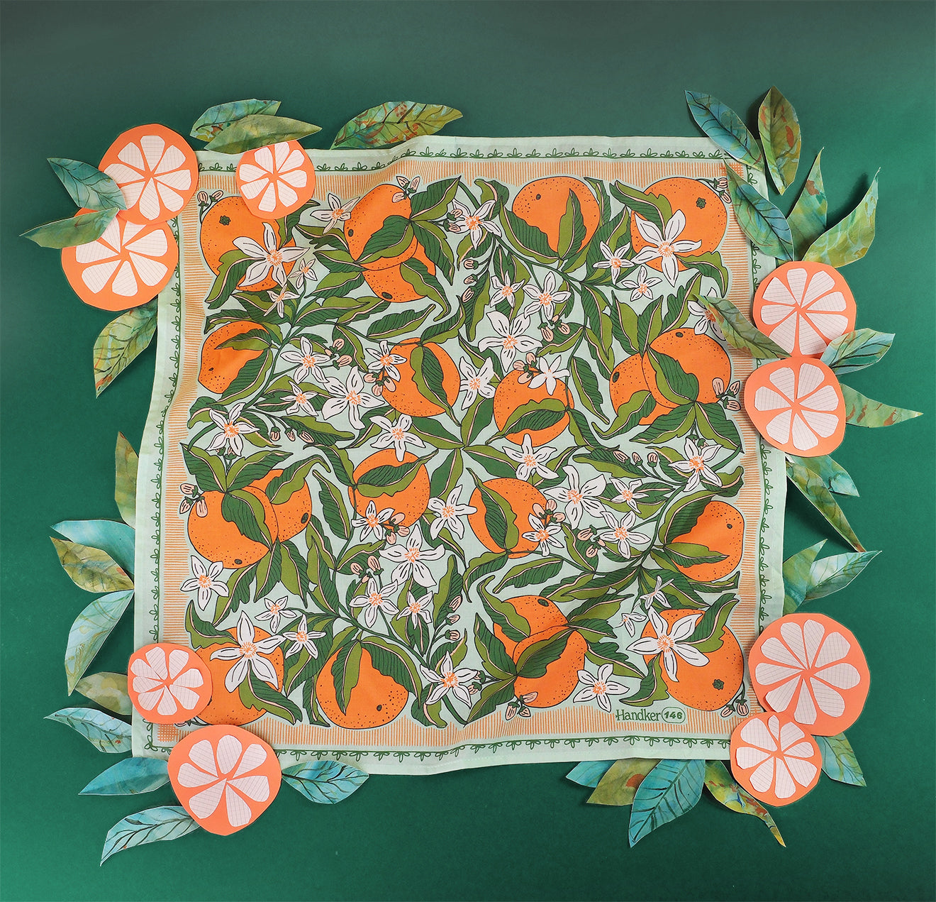 Mint bandana with oranges and white florals on a green background covered in paper oranges and leaves