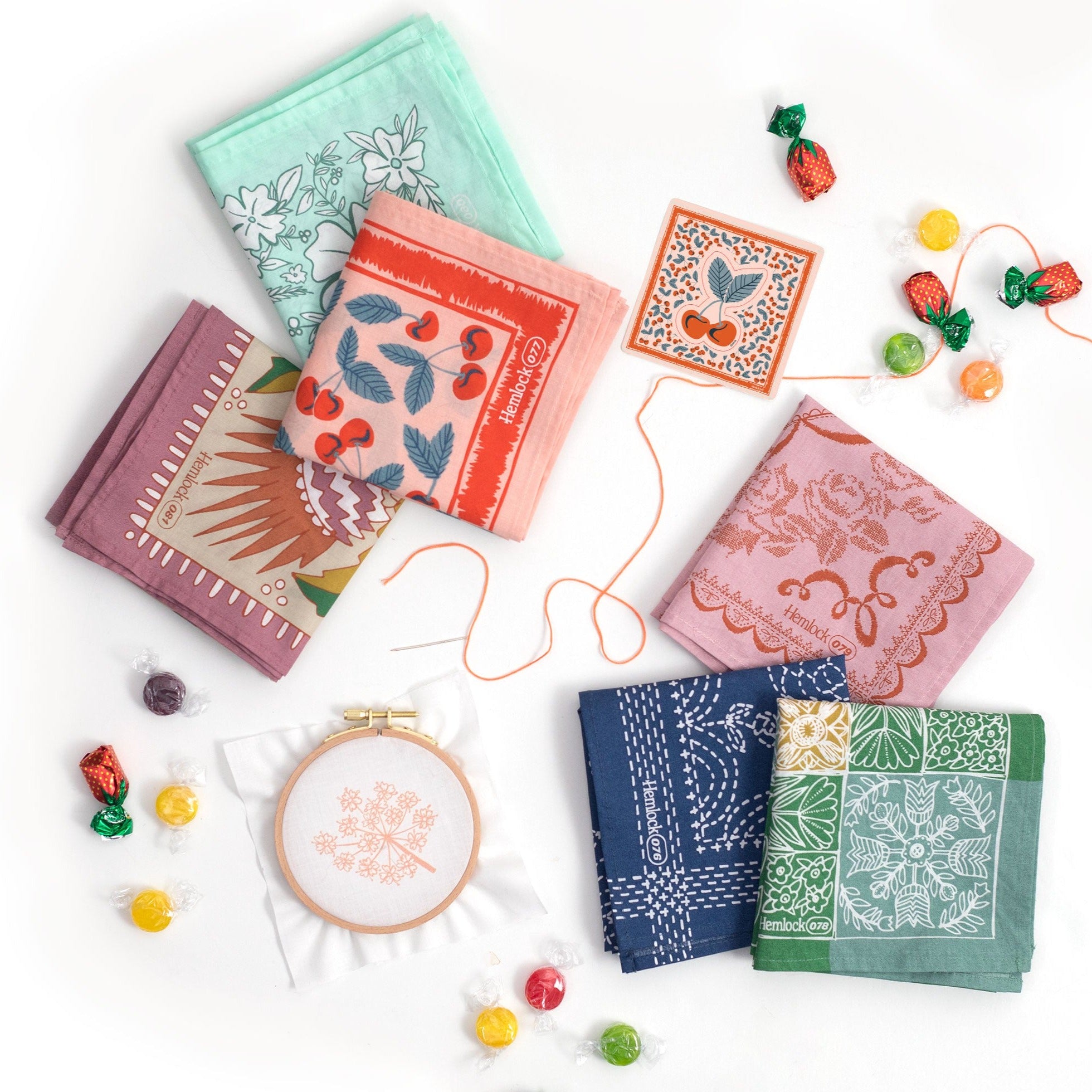 Colorful floral fabric squares with embroidery hoop and thread surrounded by candies.