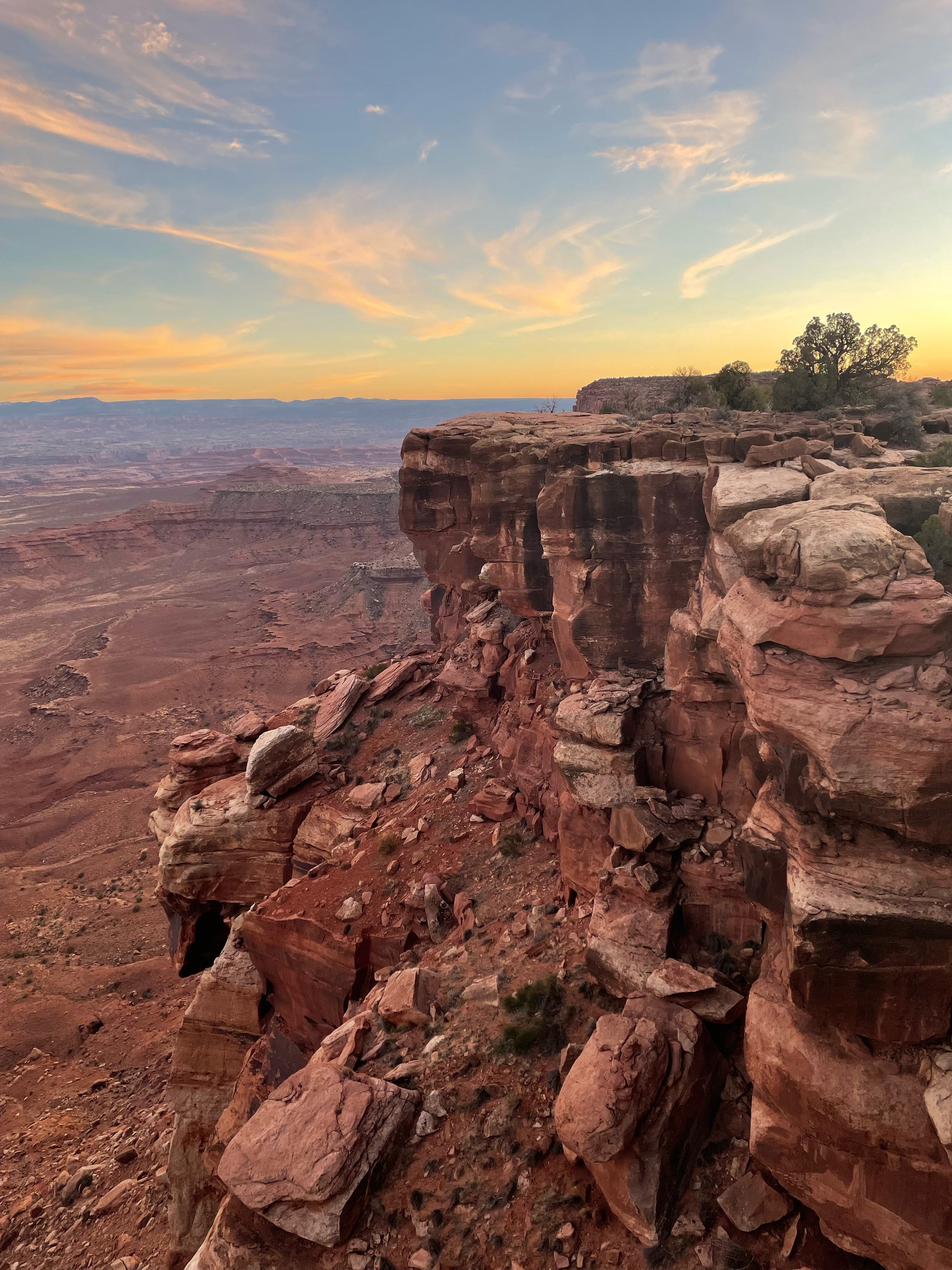 Cliff-edge overlook above red sandstone canyons near Moab at sunset with pastel clouds