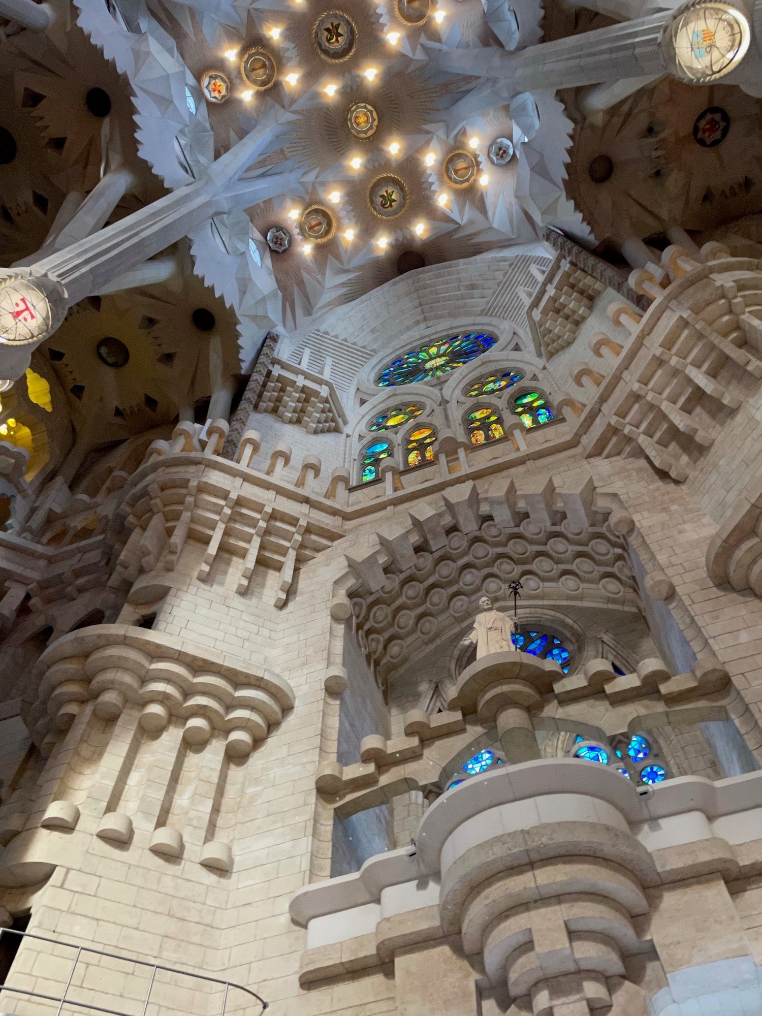 Interior of Barcelona’s Sagrada Familia with ornate stone columns, geometric ceilings, and colorful stained glass windows