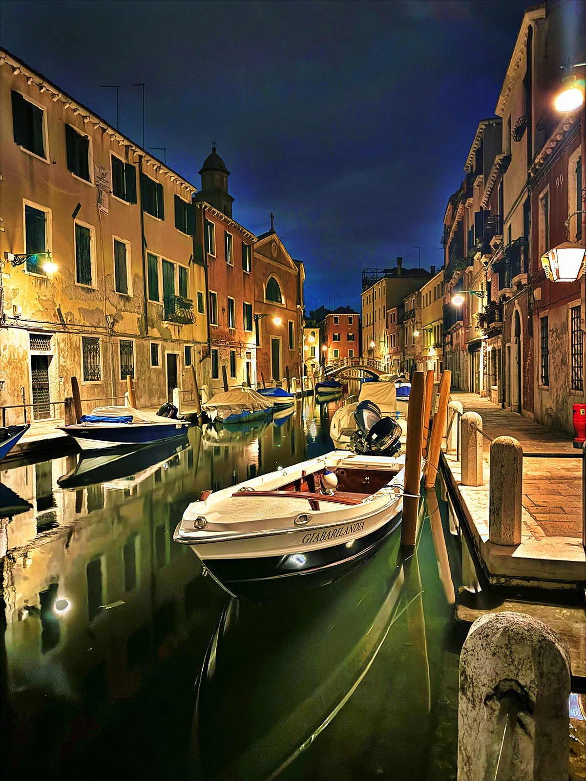 Venice canal lined with historic buildings and moored boats at night