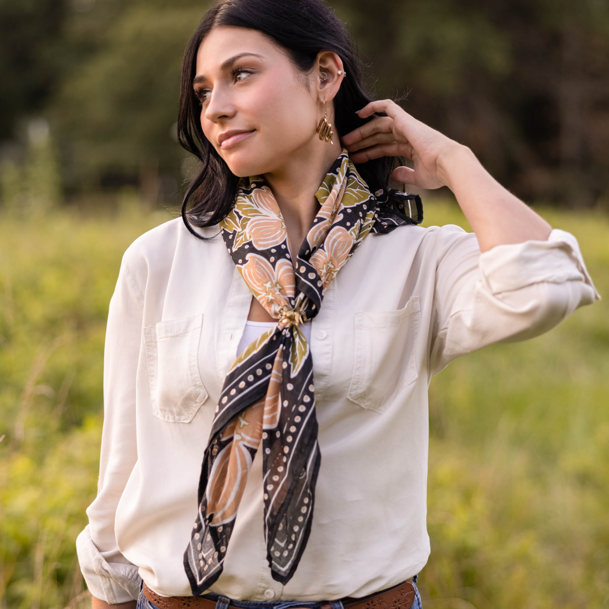Woman in white shirt with patterned scarf standing in a field