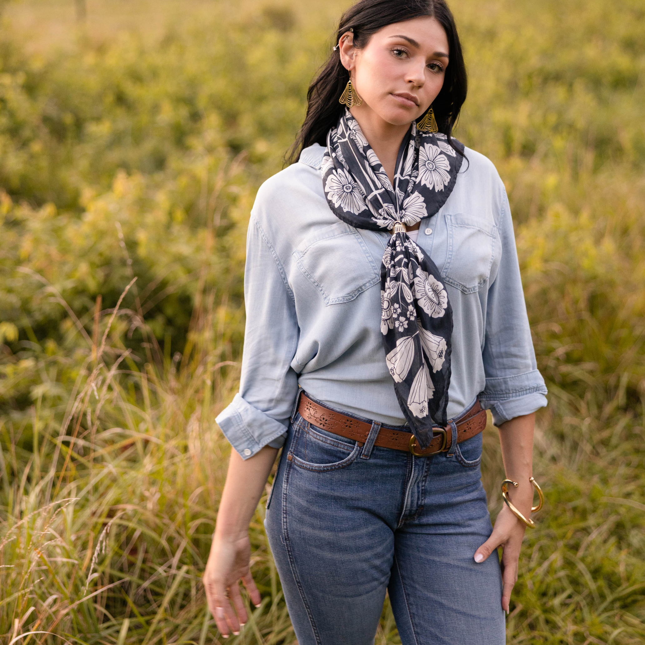 Front view of 34-inch Wild Rag 'Fiona' bandana showcasing navy and white floral print tied at model's neck in grassy field