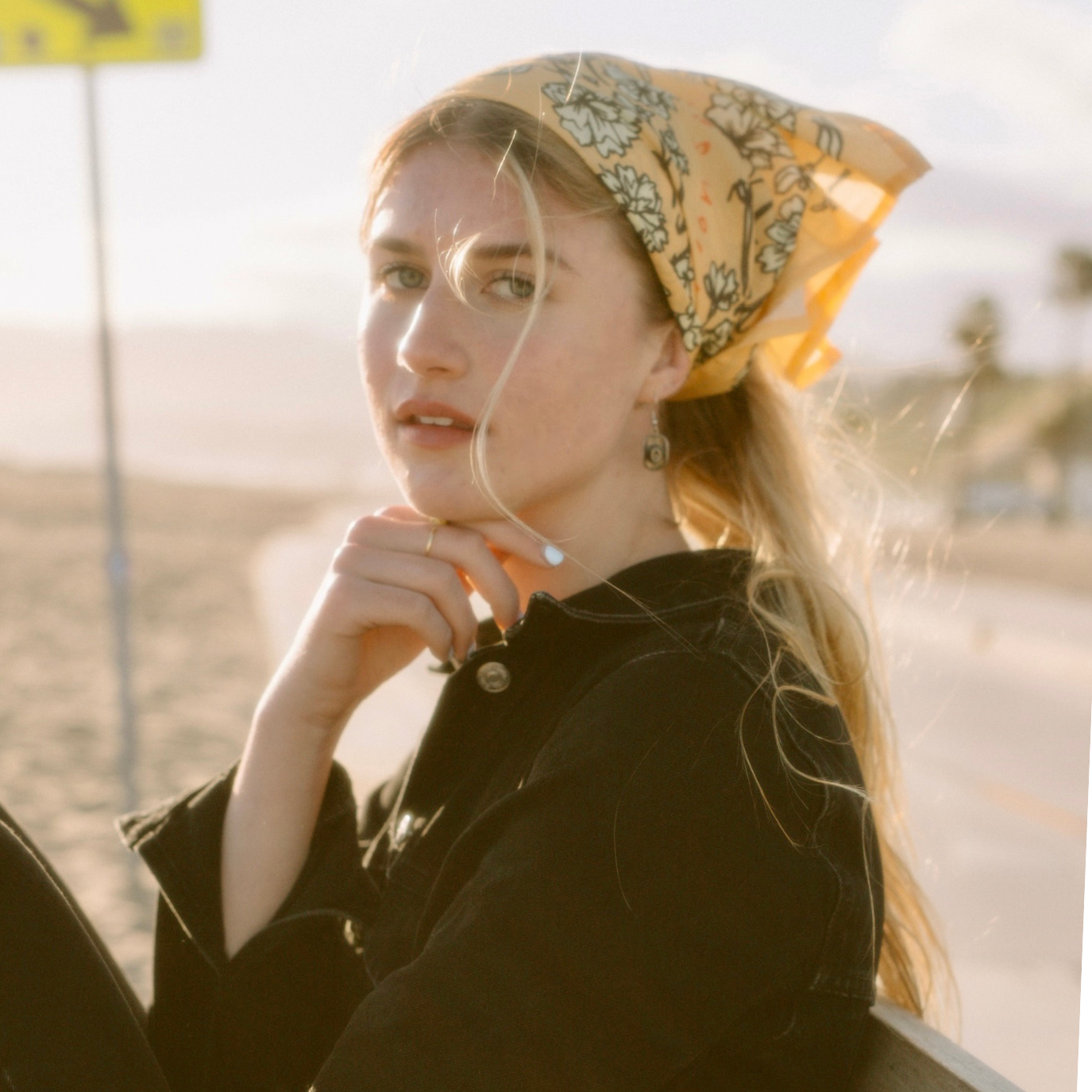 Person sitting on a bench by the beach wearing a floral headscarf