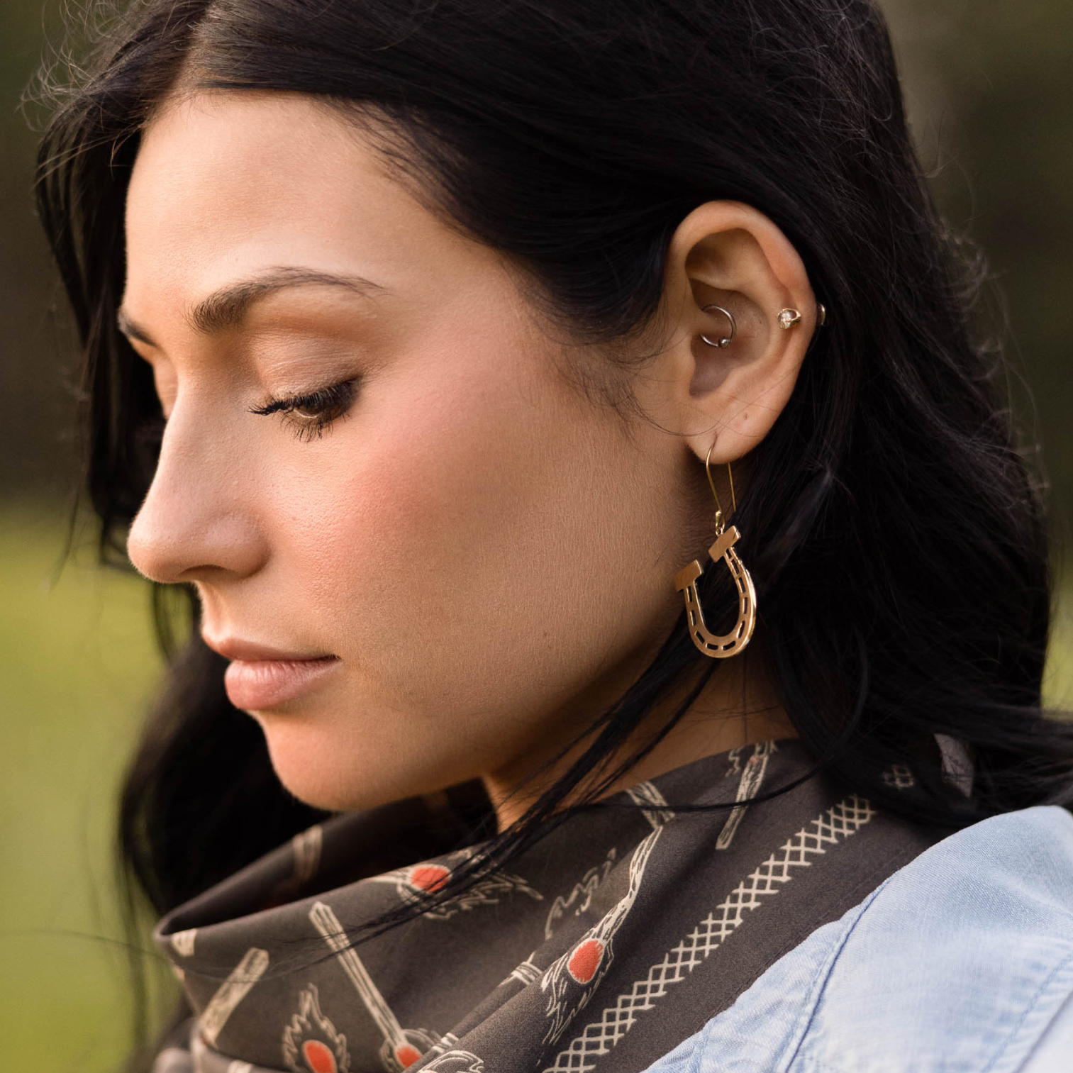 Profile of woman wearing a scarf and hoop earrings outdoors