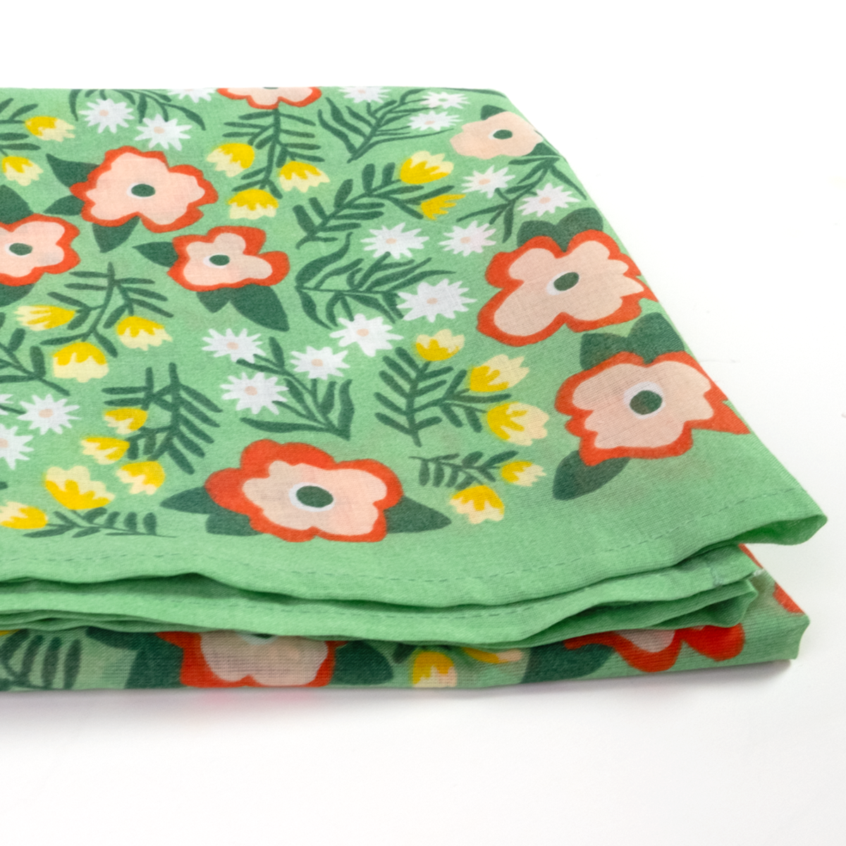 A folded piece of green fabric with a retro floral pattern featuring orange, pink, and white flowers with green leaves.