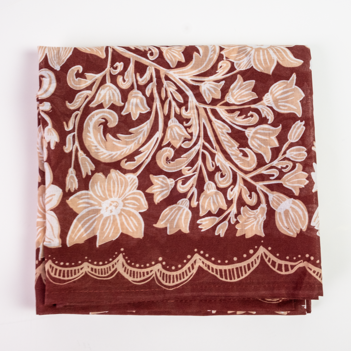 A folded square cotton bandana, featuring a deep reddish-brown background with a cream-colored floral and vine pattern and a scalloped border.