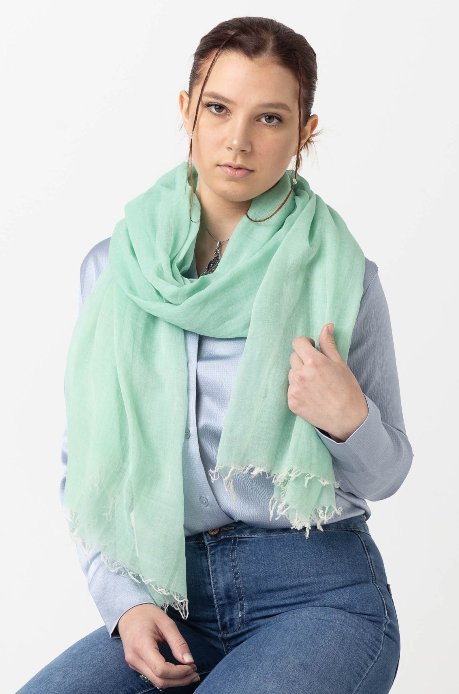 Person wearing a light blue shirt and mint green scarf