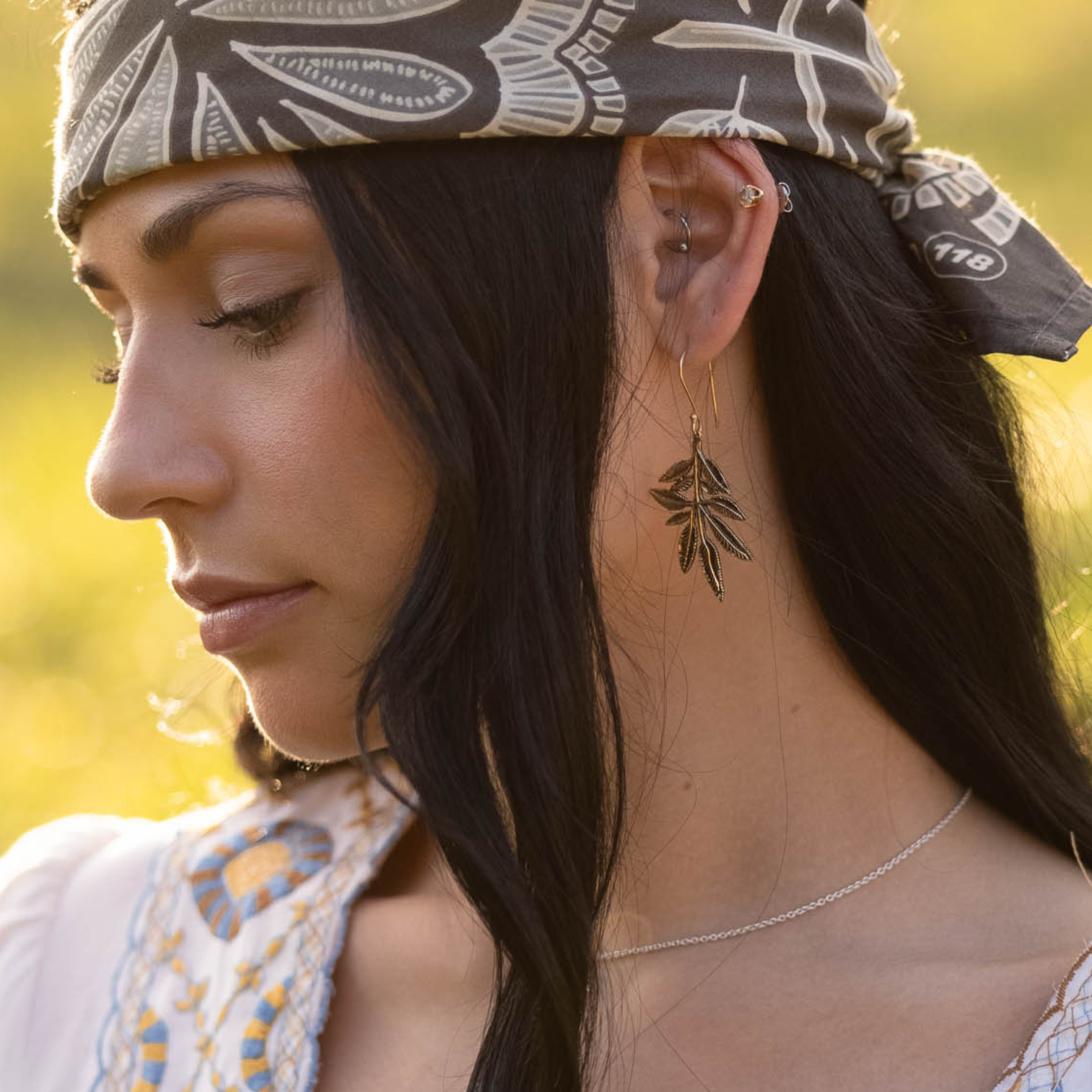 Woman wearing a patterned bandana and leaf-shaped earrings