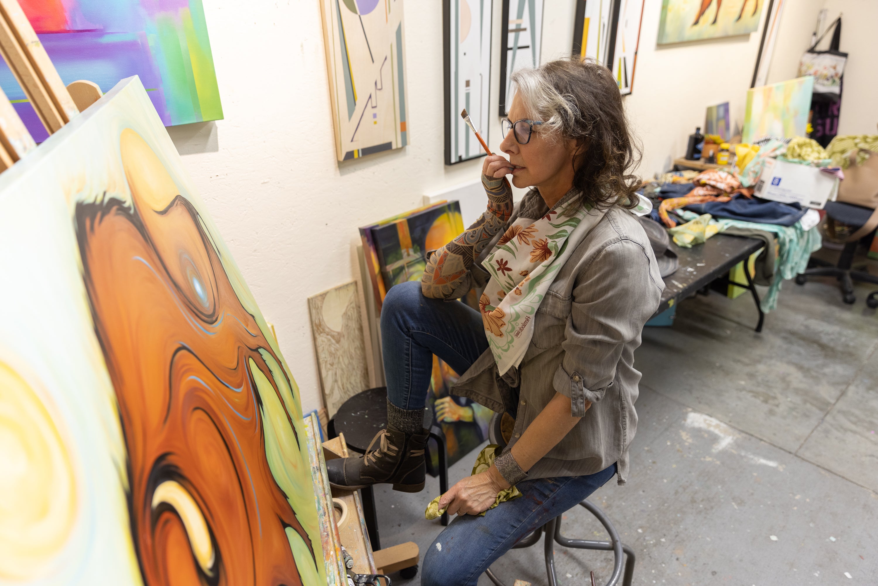 Artist painting in a studio with various artworks on the walls.