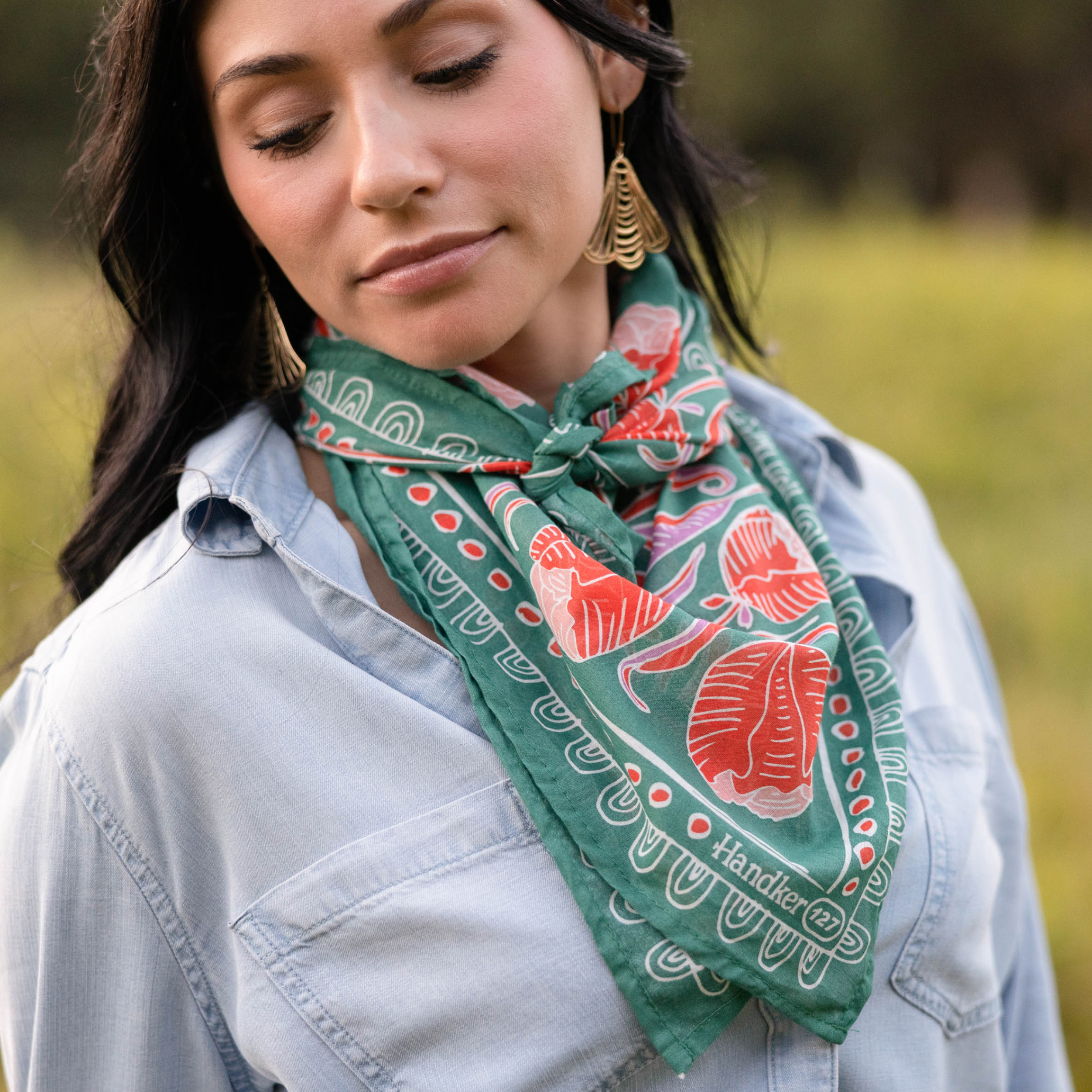 Person wearing a patterned green bandana and a denim shirt outdoors