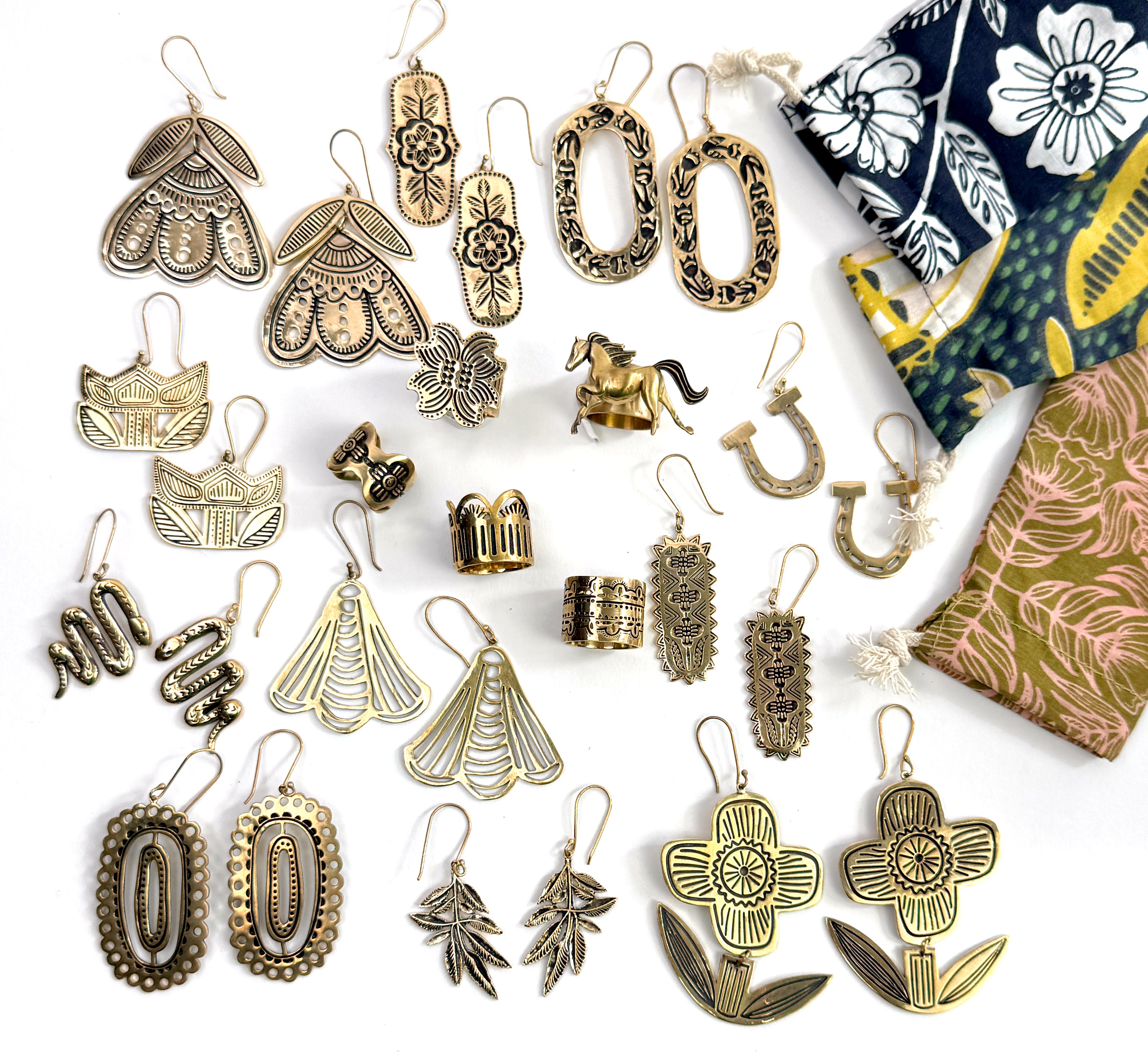 Assorted brass earrings with decorative patterns and colorful pouches