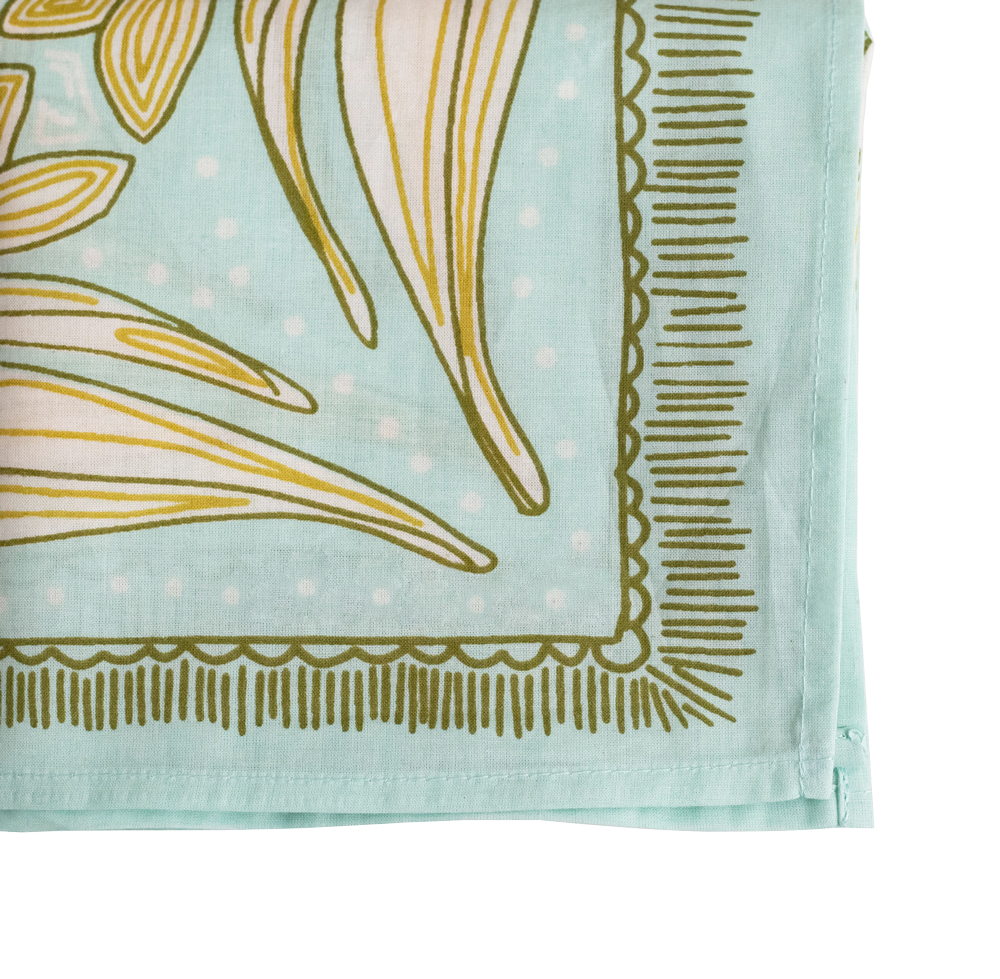 Close-up of a patterned fabric with floral motifs and a decorative border on a light blue background.