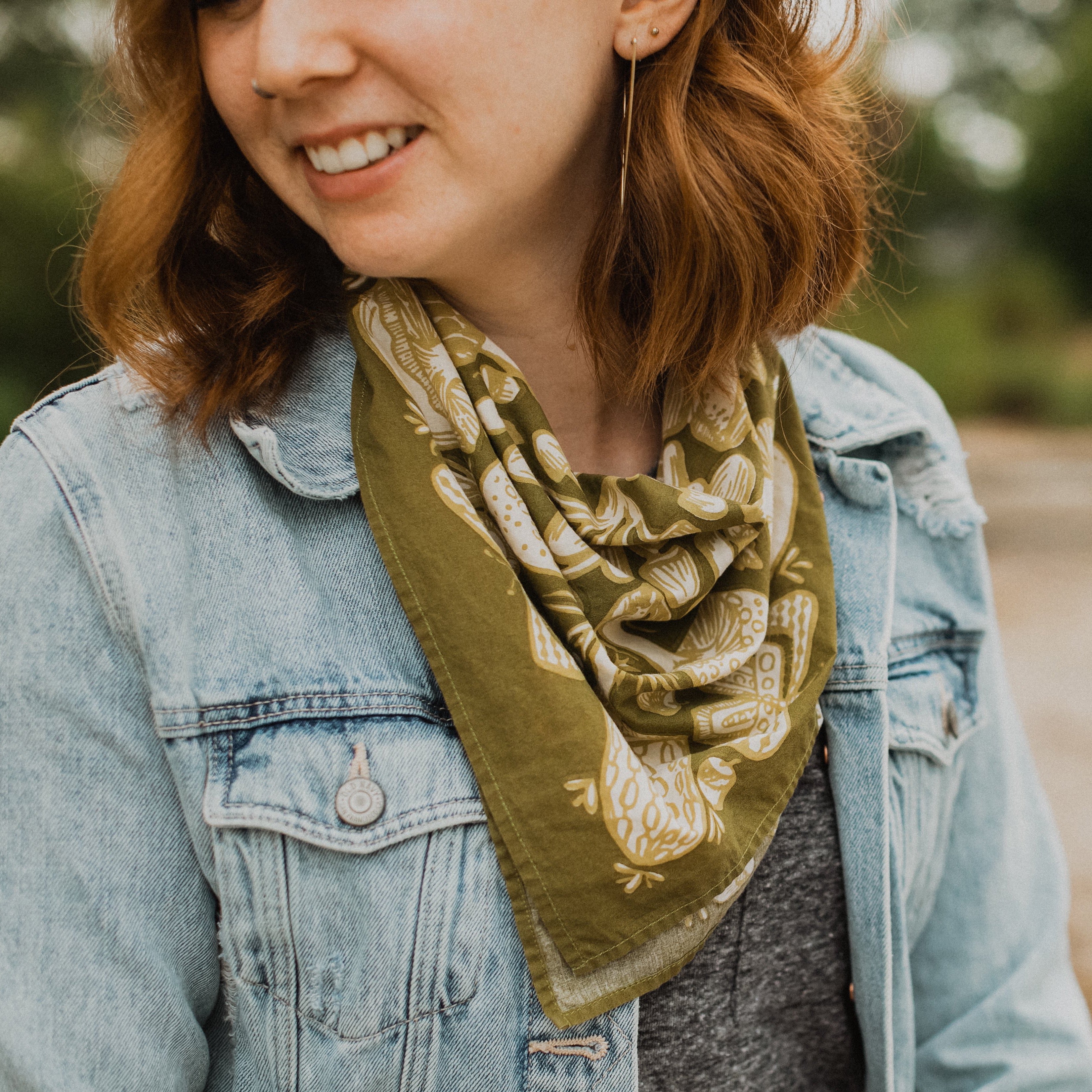 Woman wearing a green scarf and denim jacket outdoors