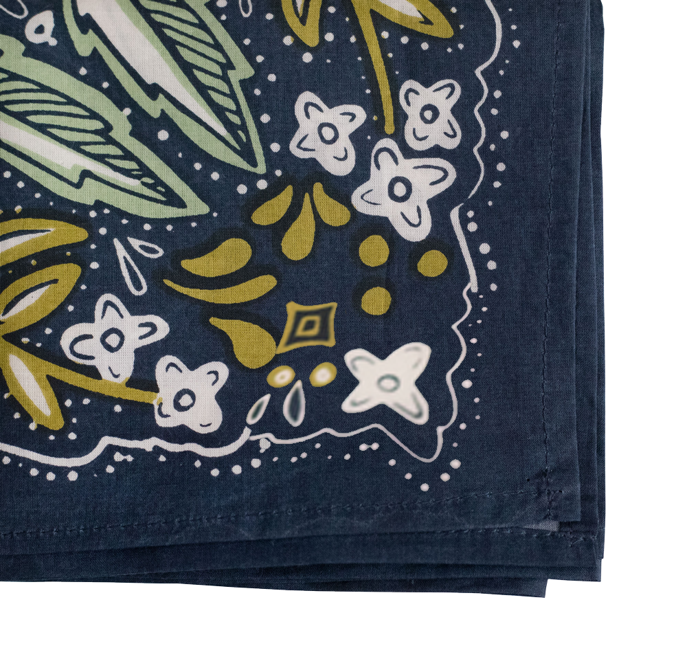 Close-up of folded corner of Amelia bandana showing green and gold floral screen-printed motif on navy cotton background