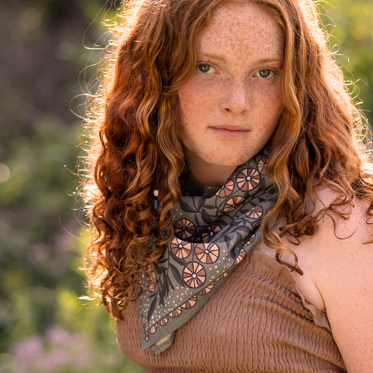 Model wearing Eleanor bandana tied at neck with warm gray floral pattern in cream, pink, mauve and muted purple