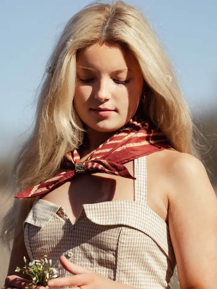 Close-up of Sammie Pink Stripe bandana tied at the neck, showing stripes and metal slide on a blurred outdoor background