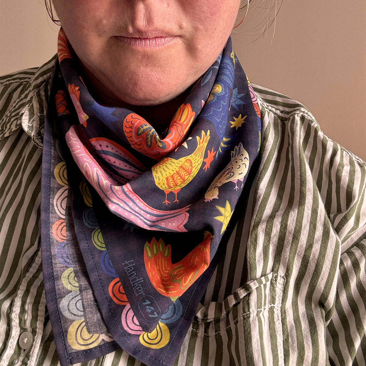 Person wearing a colorful bandana with bird designs on a neutral background