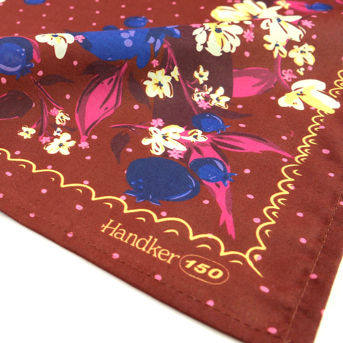 Colorful floral and blueberry patterned handkerchief with 'Handker 150' branding on a brown background.