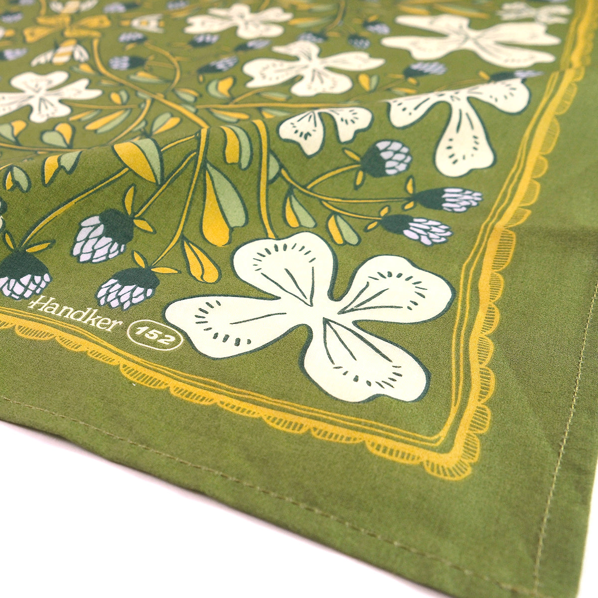 Angled close-up of No. 152 Josephine bandana showing grass green with white and lilac flowers and scalloped yellow border