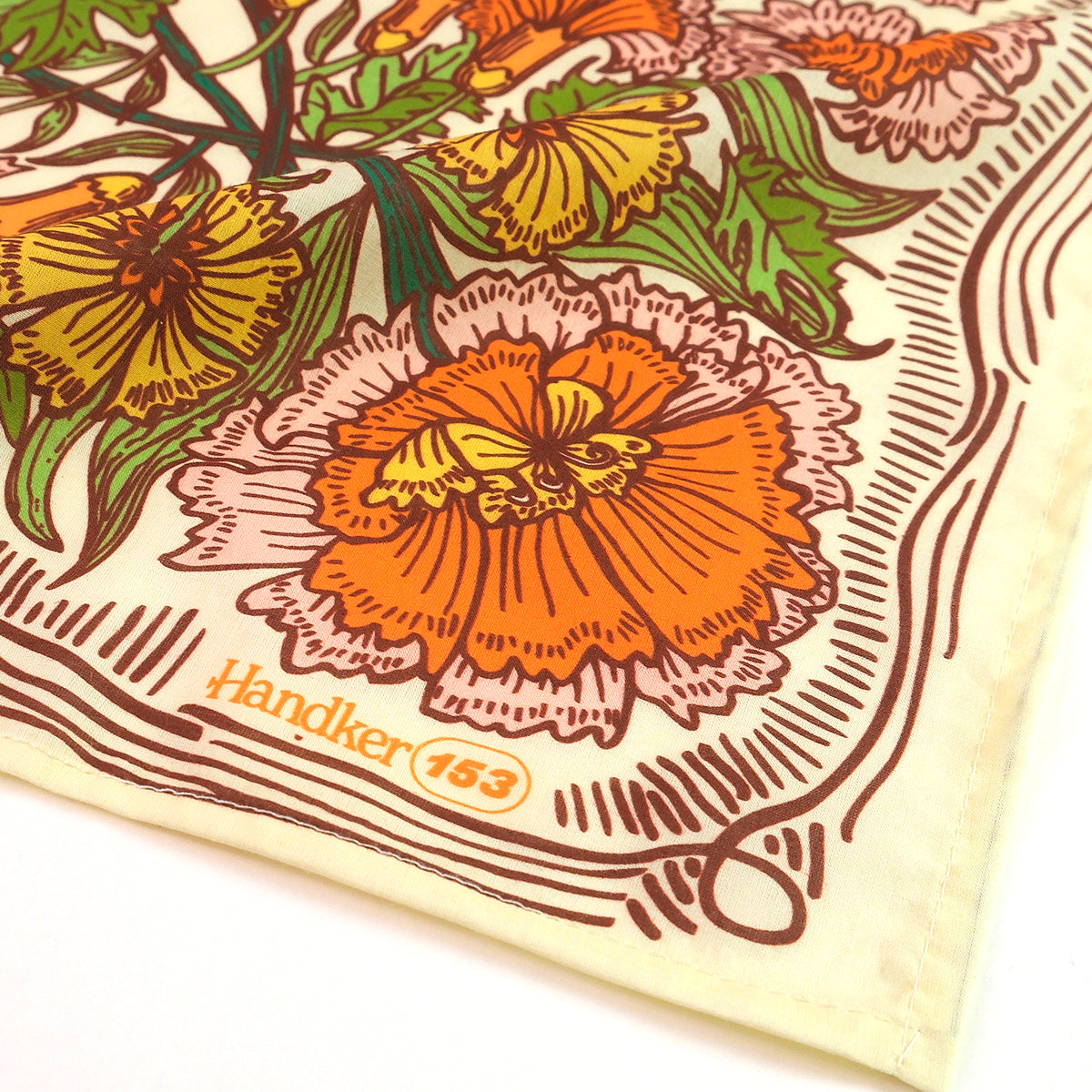 Close-up corner of No. 153 Hannah bandana showing orange and pink floral print on a cream background with a brown printed border