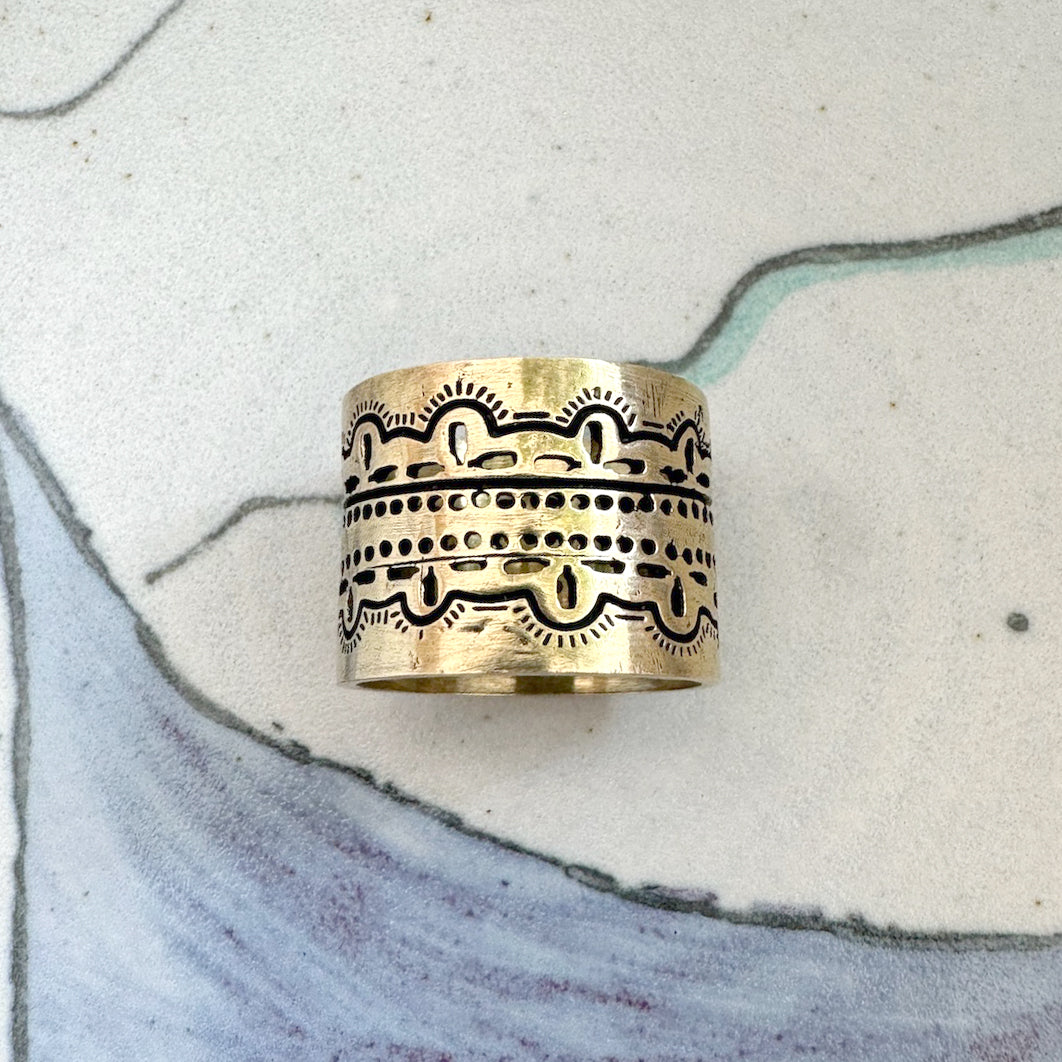 Ornate brass band ring on a decorative surface