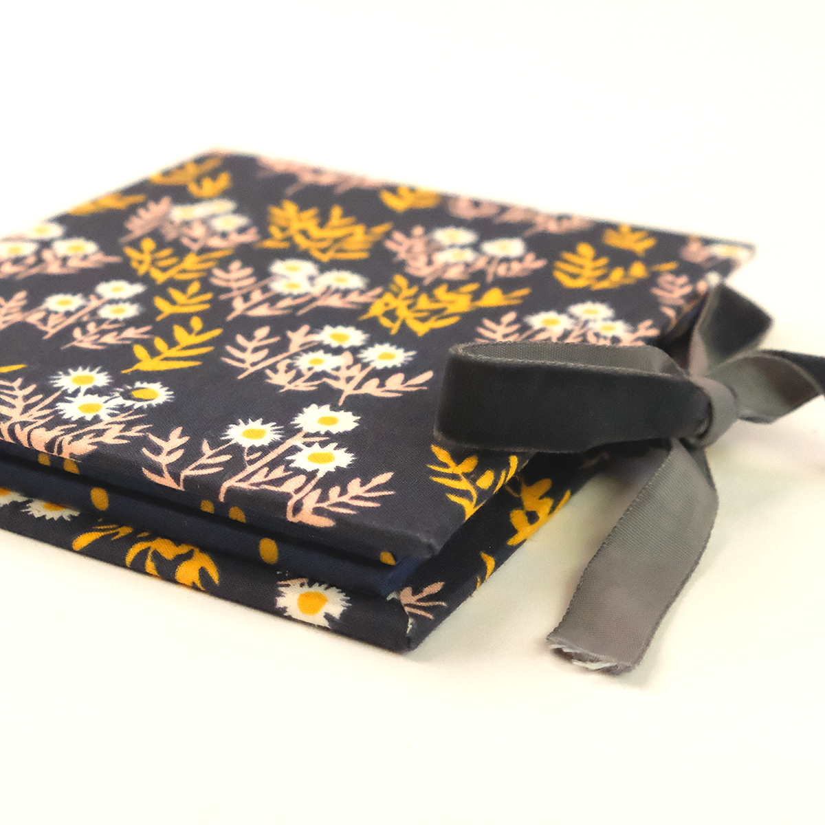 Fabric-covered gift box with navy background, yellow and white floral print and tied gray ribbon