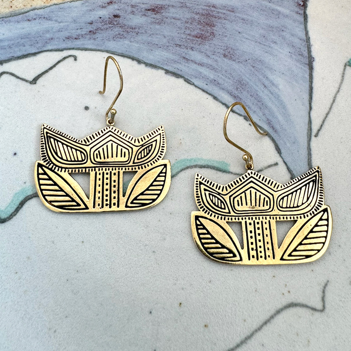 Pair of gold geometric earrings on a textured background