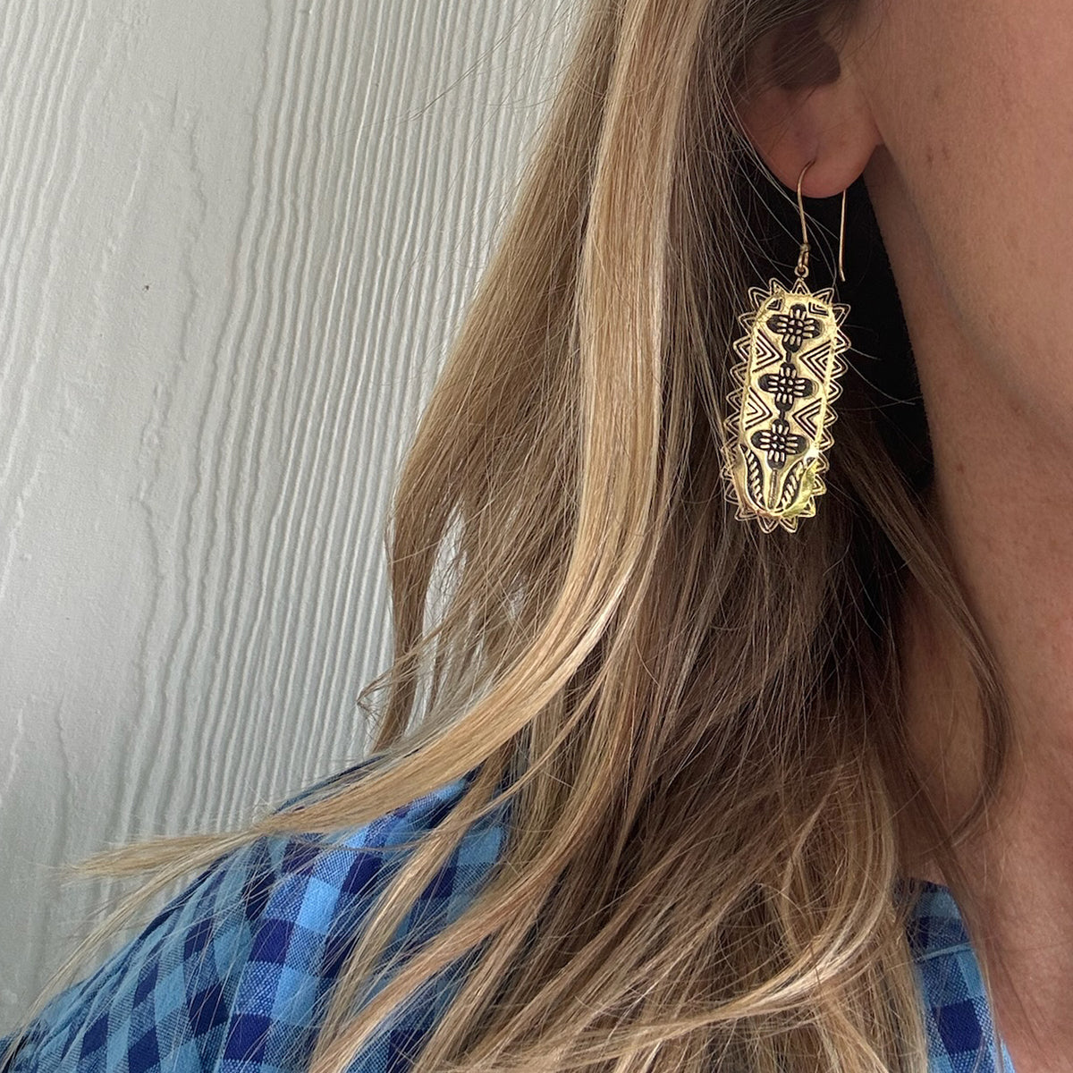 Close-up of a woman wearing a dangly geometric earring